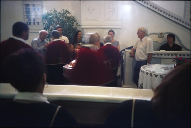 A town hall meeting from a wider angle, capturing the interaction between a speaker at the podium and the audience. The image conveys a sense of community and active participation in democratic processes.