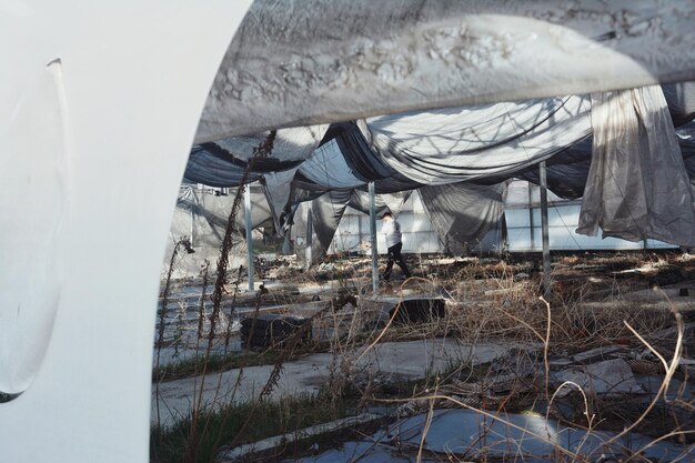 A detailed photograph showcasing damaged event infrastructure, with tipped-over tents, scattered debris, and wet ground amidst a community event location.