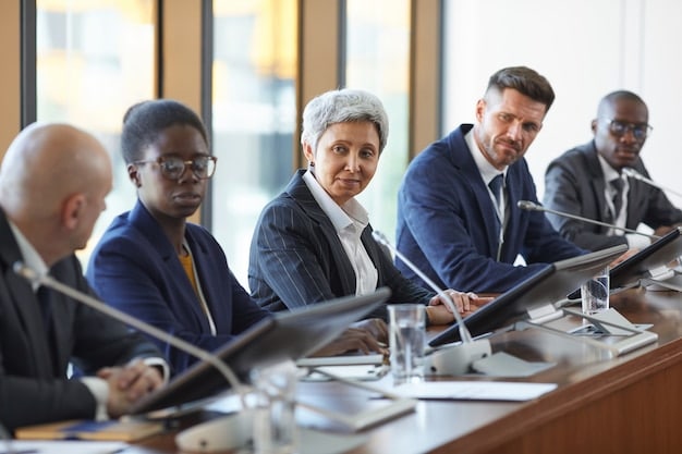 A diverse group of politicians meeting in a conference room, reviewing documents related to State budgets and grant allocations.